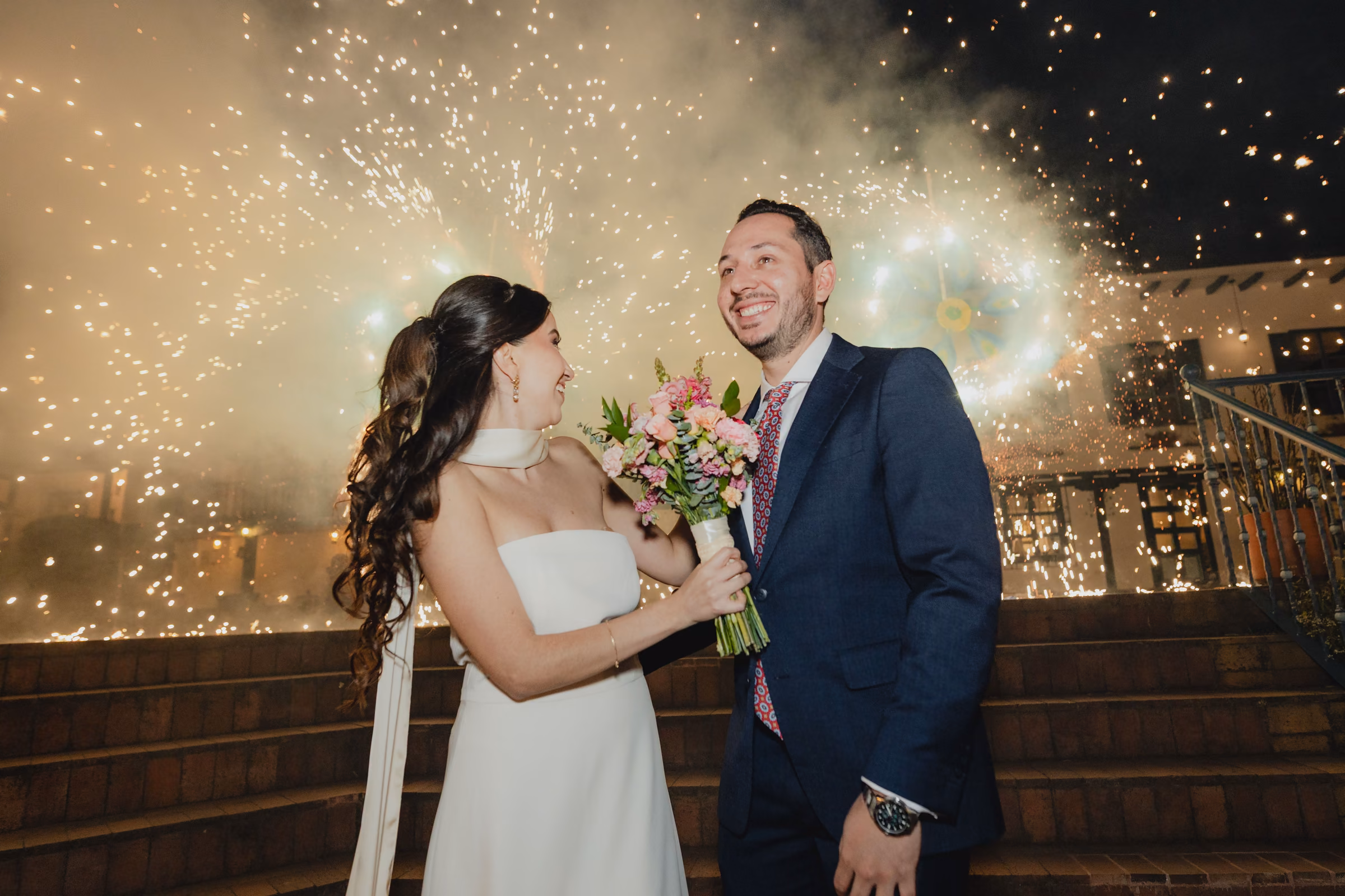 Los novios entre una cortina de chispas frías, de noche en el patio de Estancia Rosario.